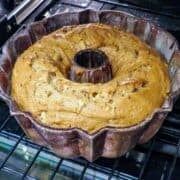 A bundt pan with a fresh apple cake in the oven.