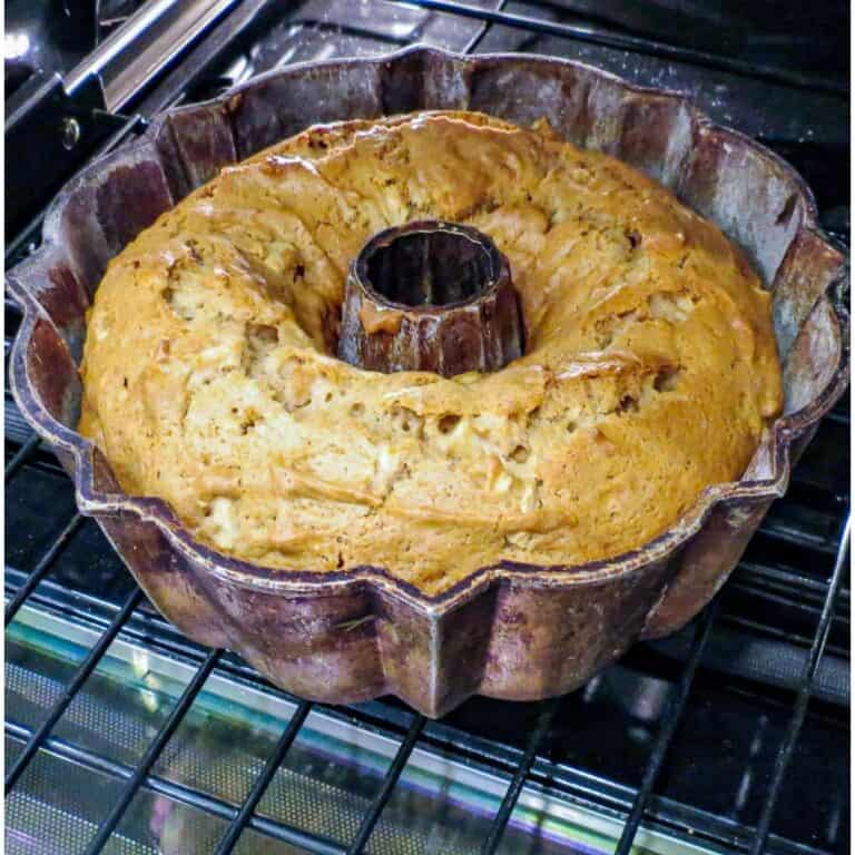 A bundt pan with a fresh apple cake in the oven.