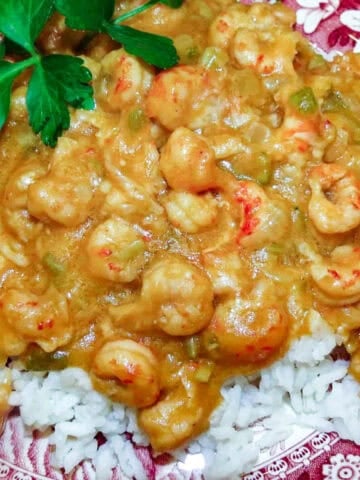Crawfish etouffee over white rice with parsley garnish.