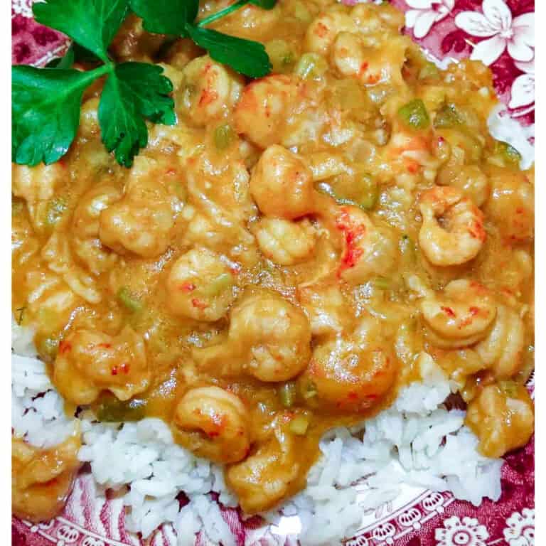 Crawfish etouffee over white rice with parsley garnish.