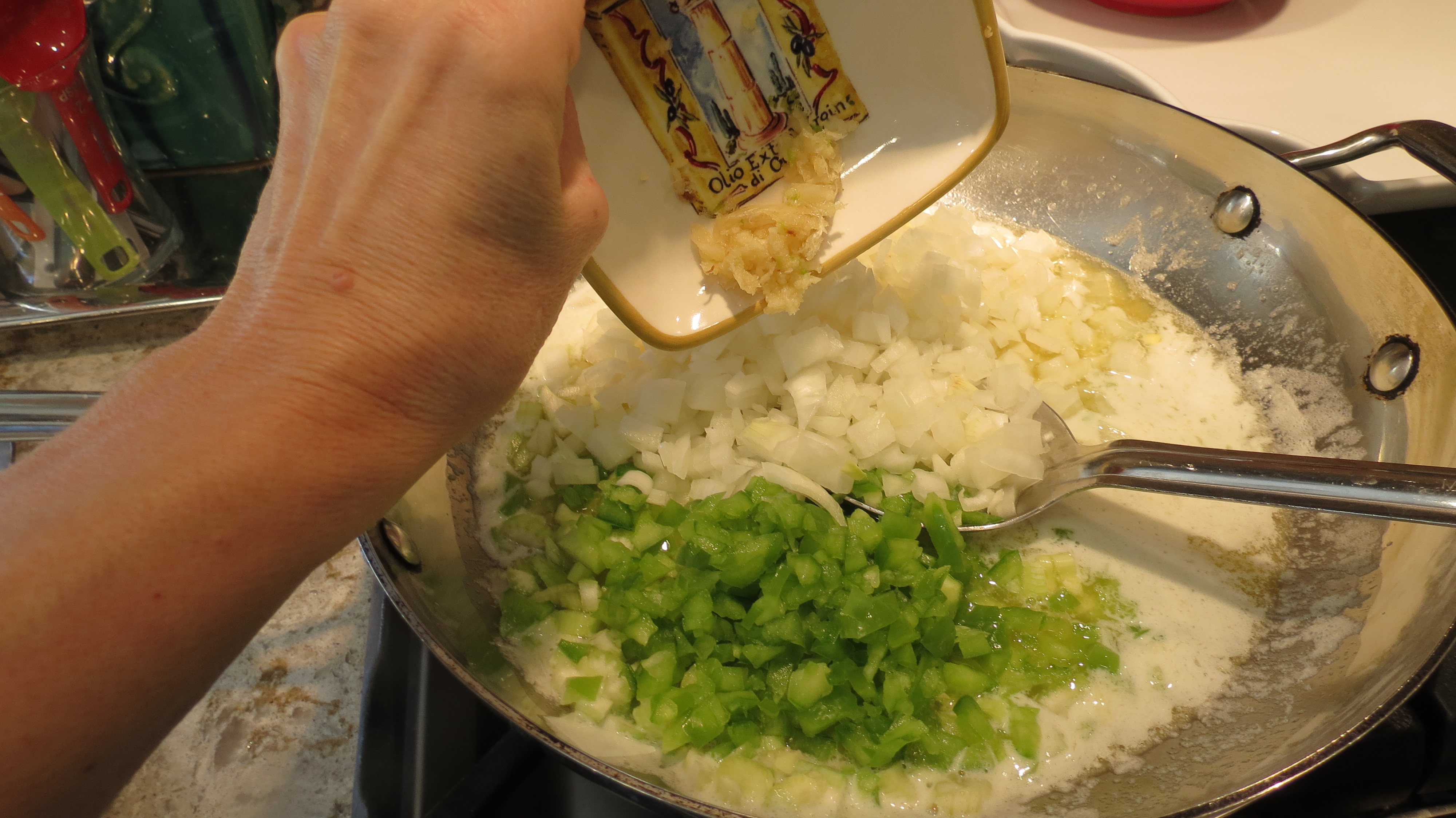Adding garlic to crawfish étouffée.