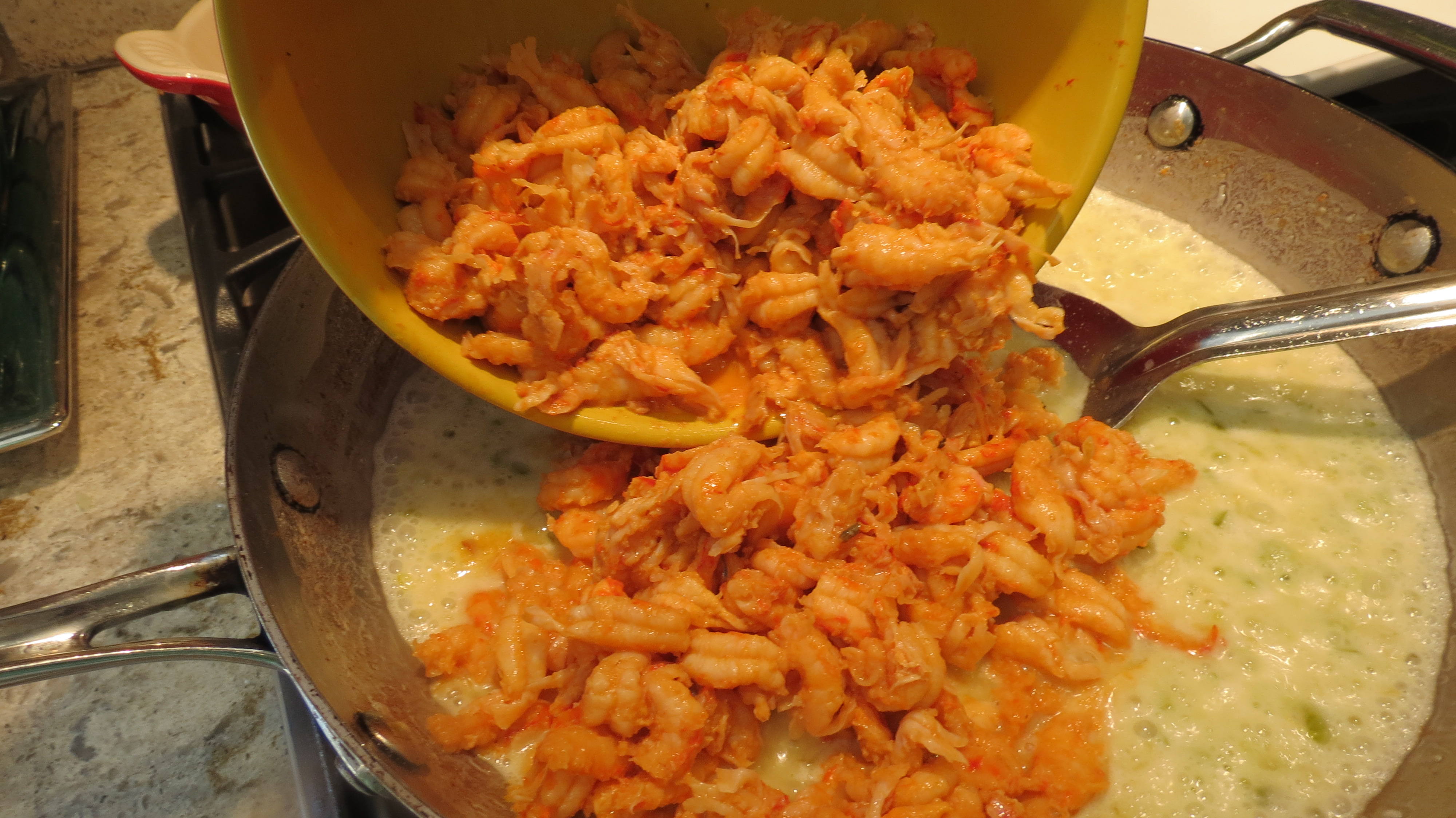Adding the crawfish to pan for crawfish étouffée.