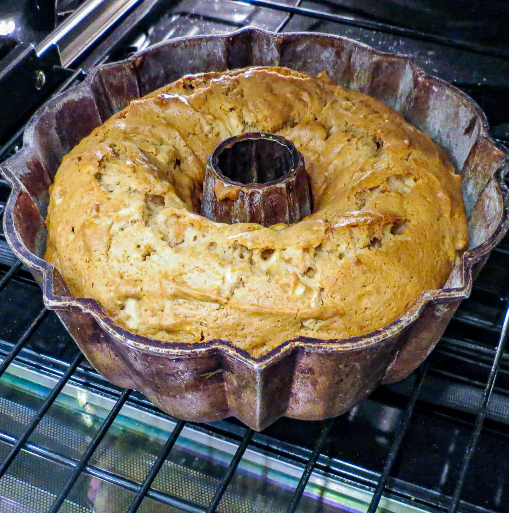 A bundt pan with a fresh apple cake in the oven.