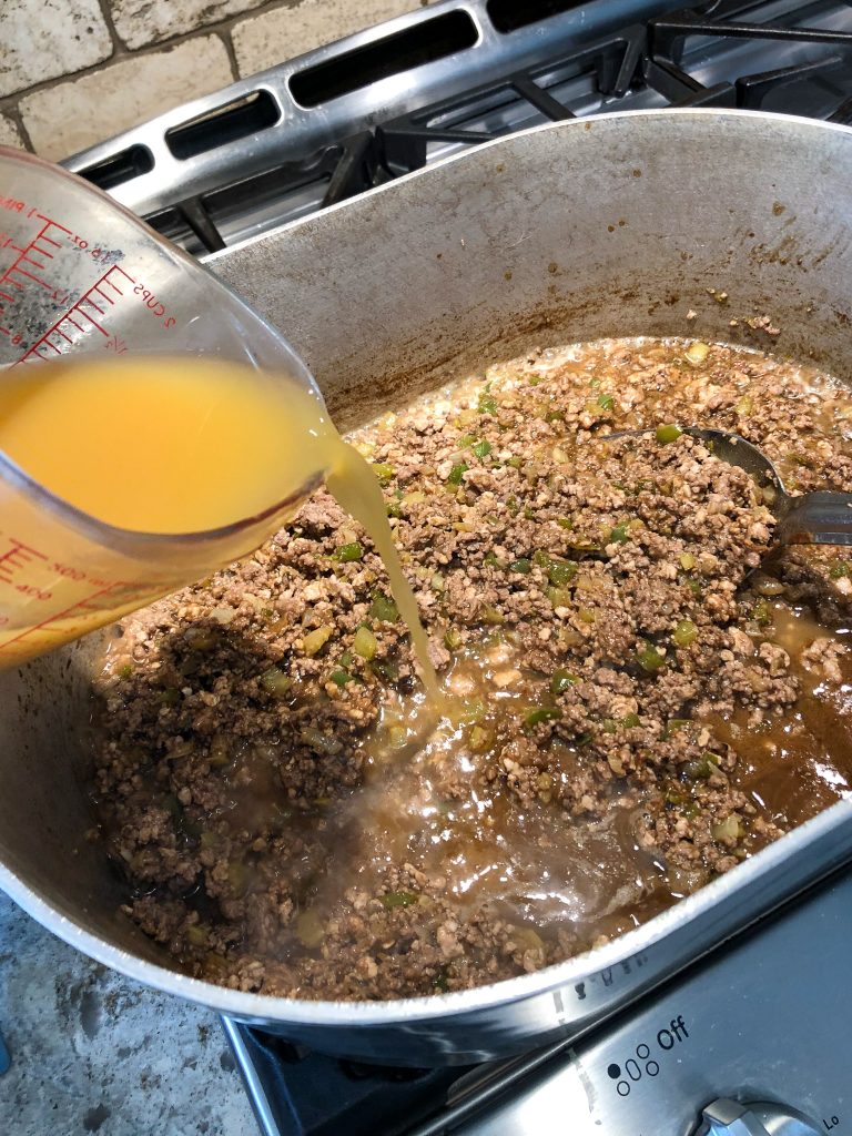 A cup of broth poured into stewed ground meat.
