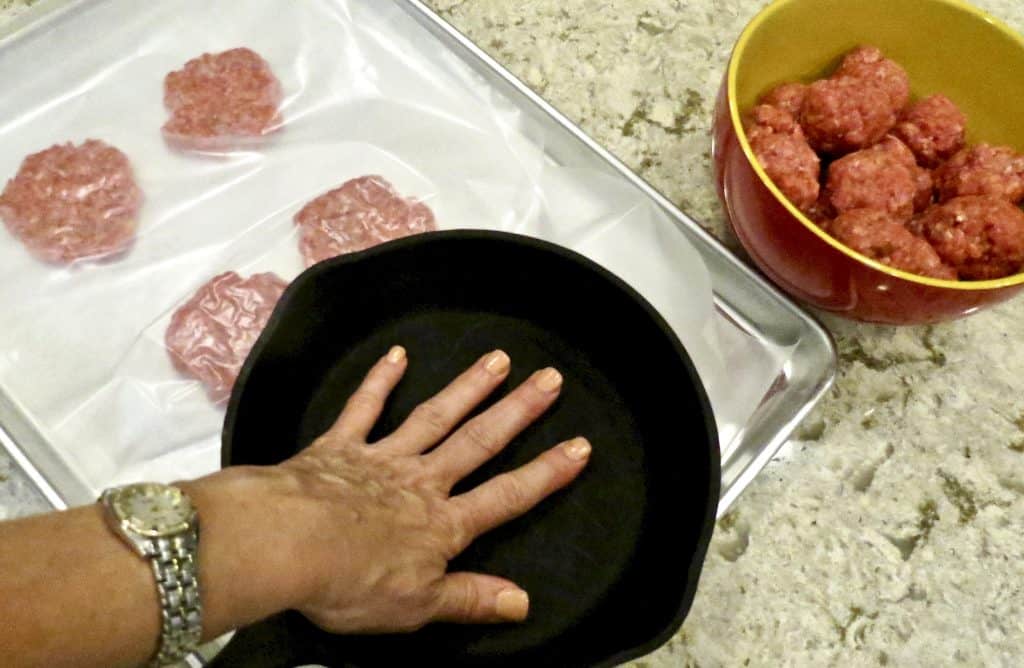 Hamburger patties pressed between wax paper with an iron skillet.