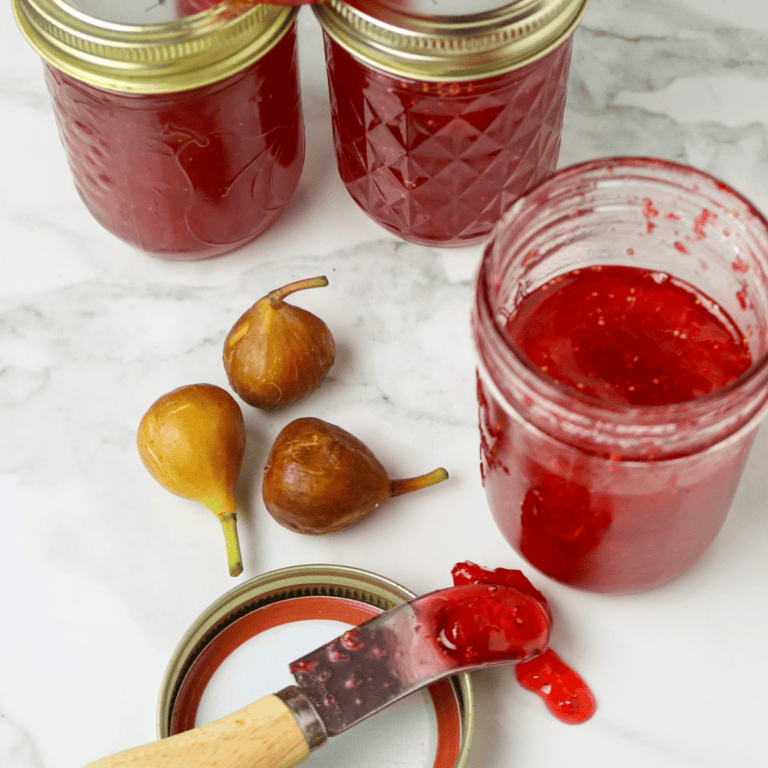 Three jars of jam with fresh figs beside them.