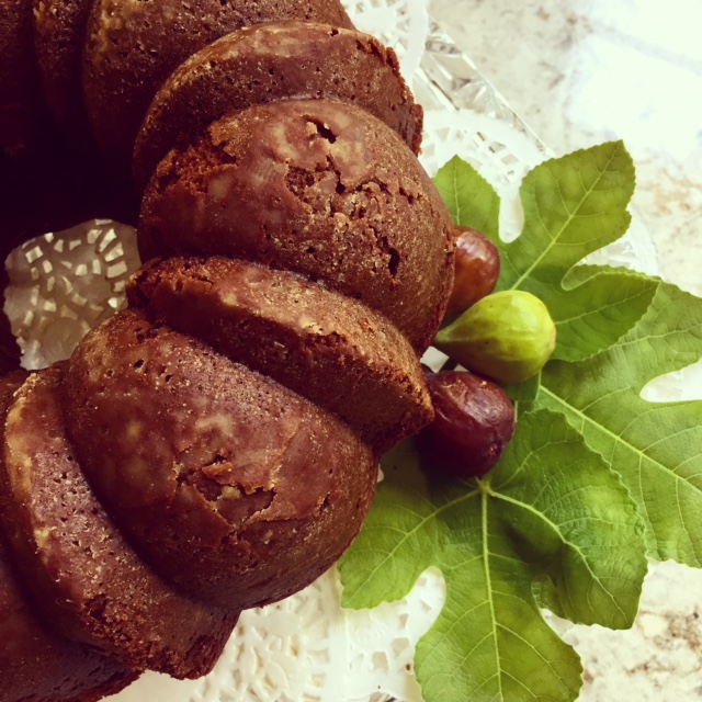 Fig cake on lace doily and fig leaves with fresh figs.