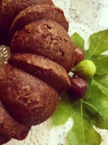 A bundt-style fig cake with fresh figs and fig leaves.