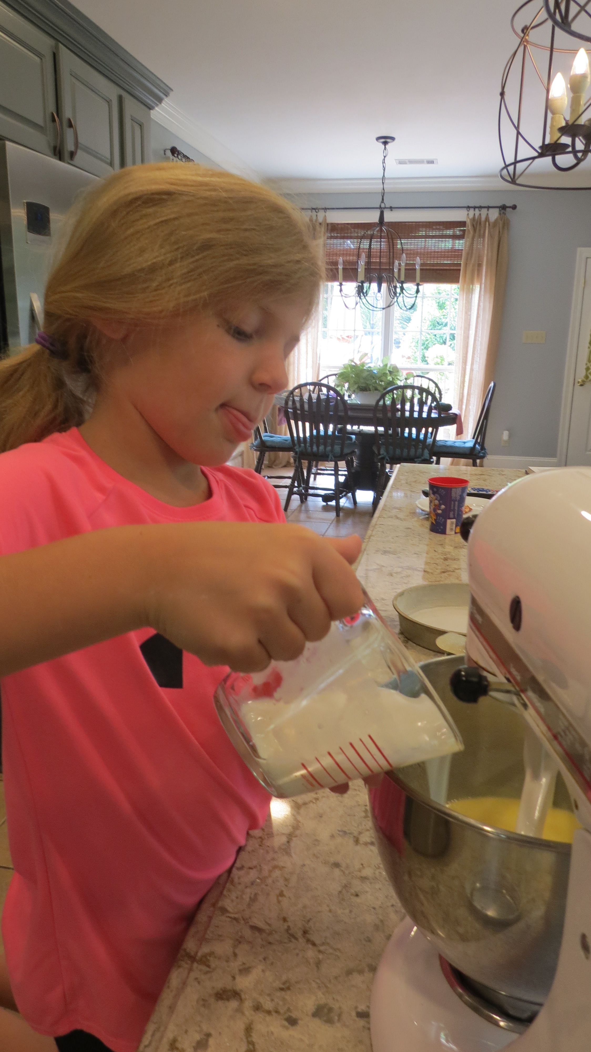 Little girl pouring buttermilk into a mixing bowl.