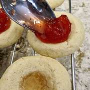 Spooning fig preserves into thumbprint in Fig Tart Cookies.