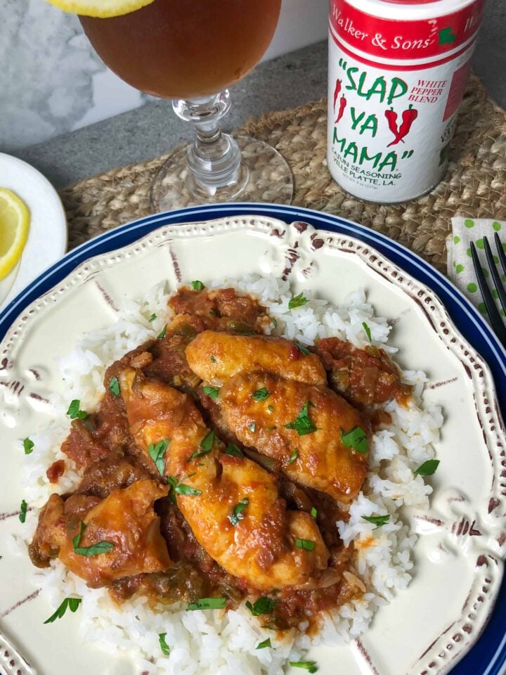 A plate of white rice topped with Fish In Red Gravy.