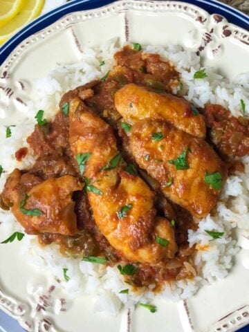 A plate of white rice topped with Fish In Red Gravy.