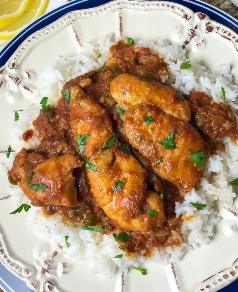 A plate of white rice topped with Fish In Red Gravy.