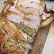 A sliced baked stuffed chicken on a board.
