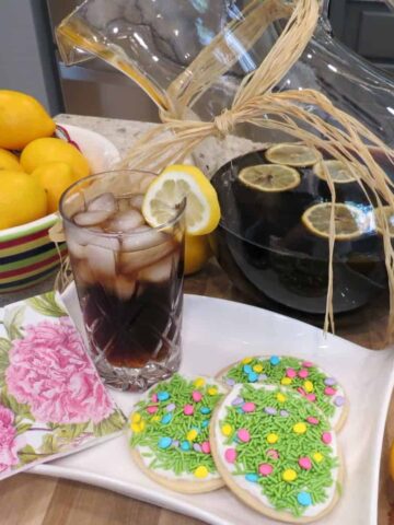 A pitcher of root beer with a filled glass and cookies.