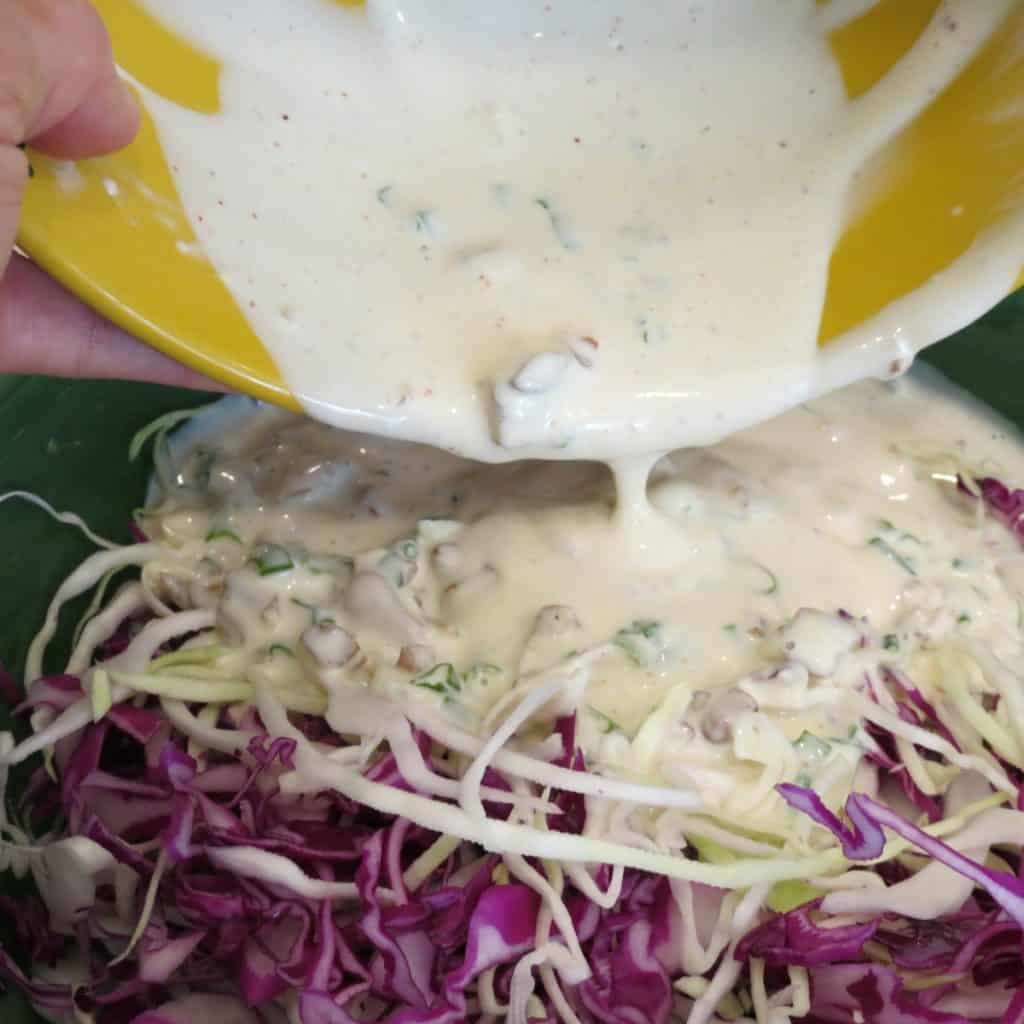 Dressing poured over cabbage for Southern Louisiana Coleslaw