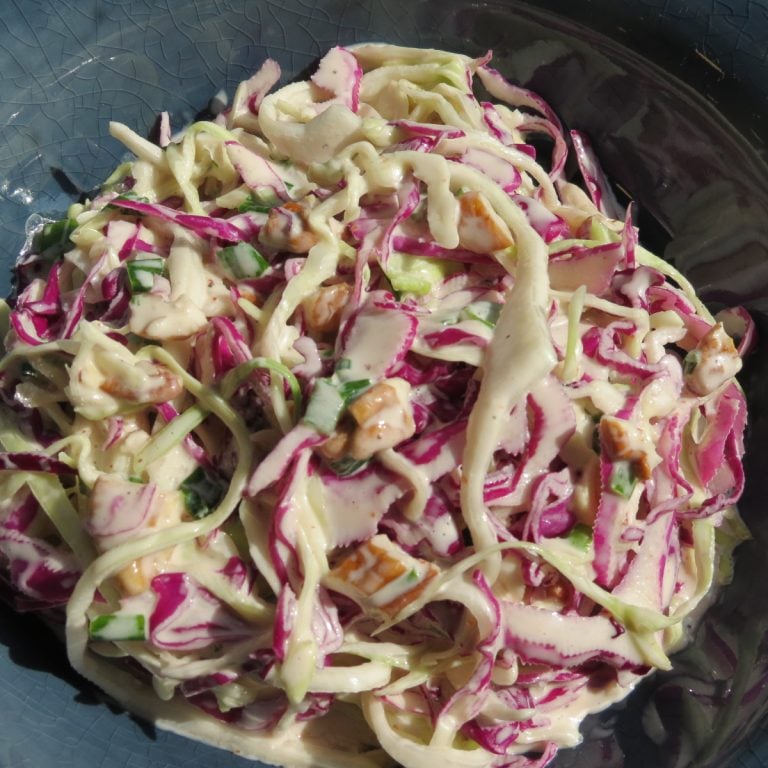 A bowl of red and green cabbage in a white sauce.