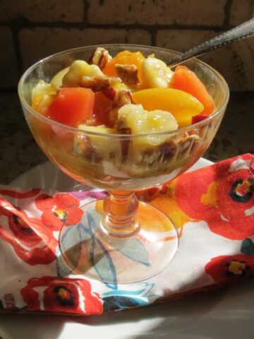 A stemmed dessert cup filled with fruit salad.