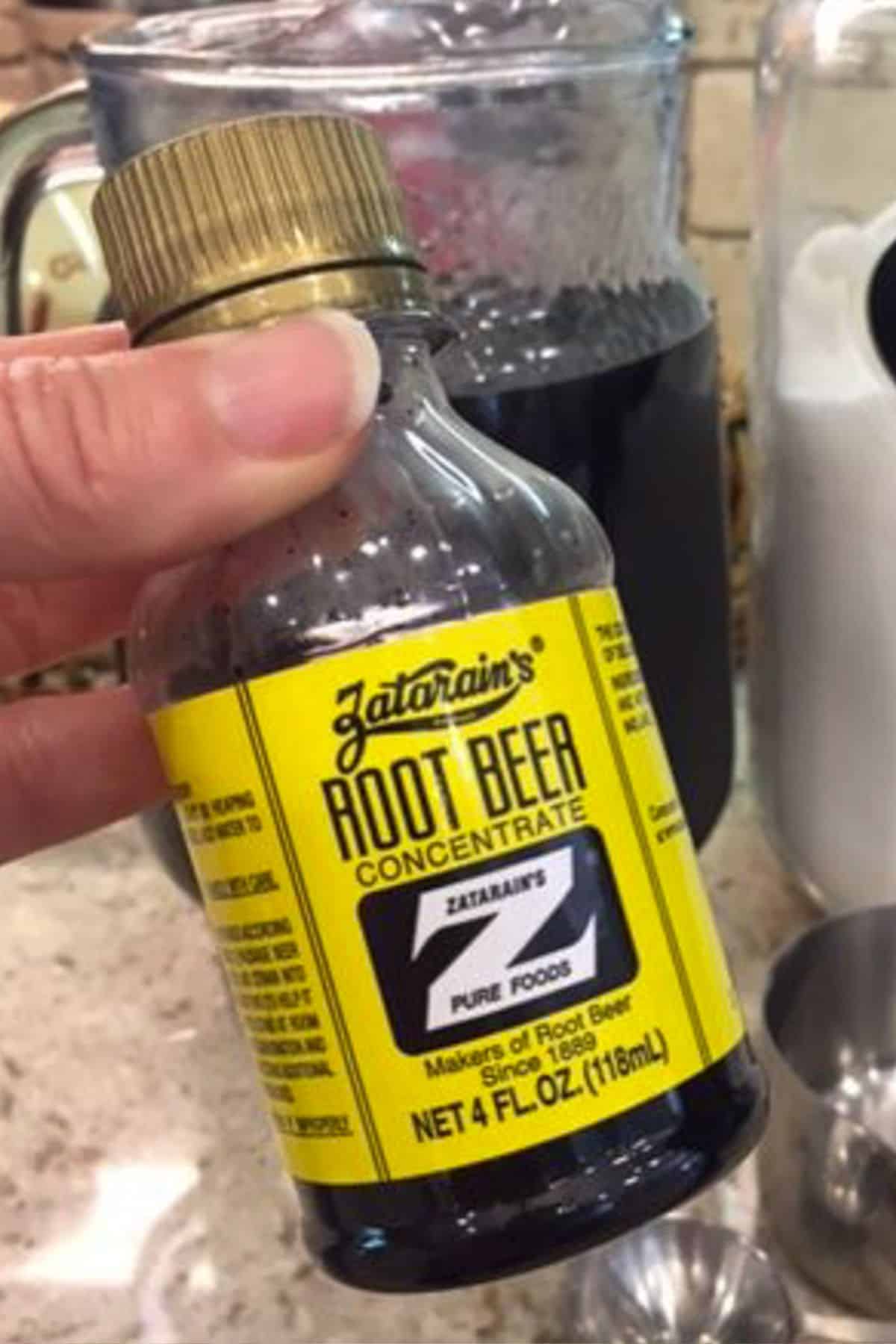 Fingers holding up a small bottle of Zatarain's root beer.