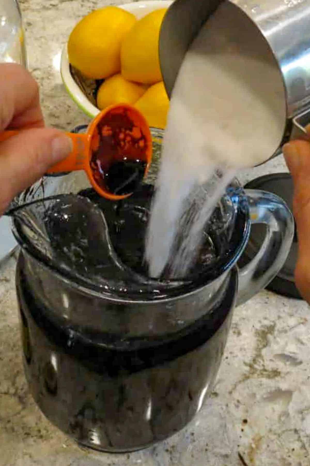 A glass pitcher with sugar and a tablespoon of root beer concentrate poured into it.
