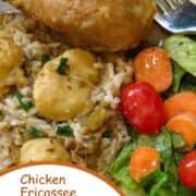 A plate of chicken fricassee with rice, gravy, chicken, dumplings, and salad.