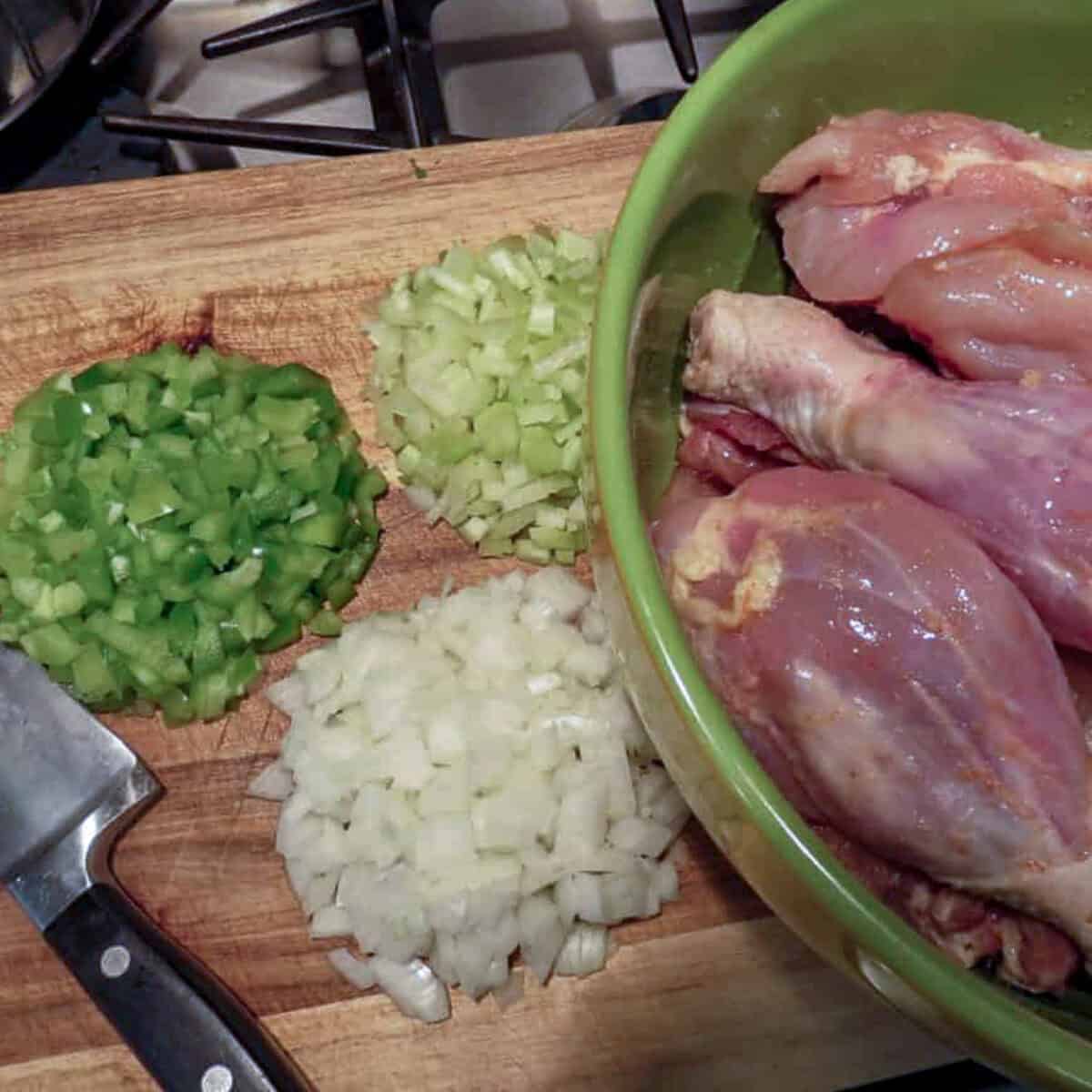 A bowl of chicken and onions on a cutting board.