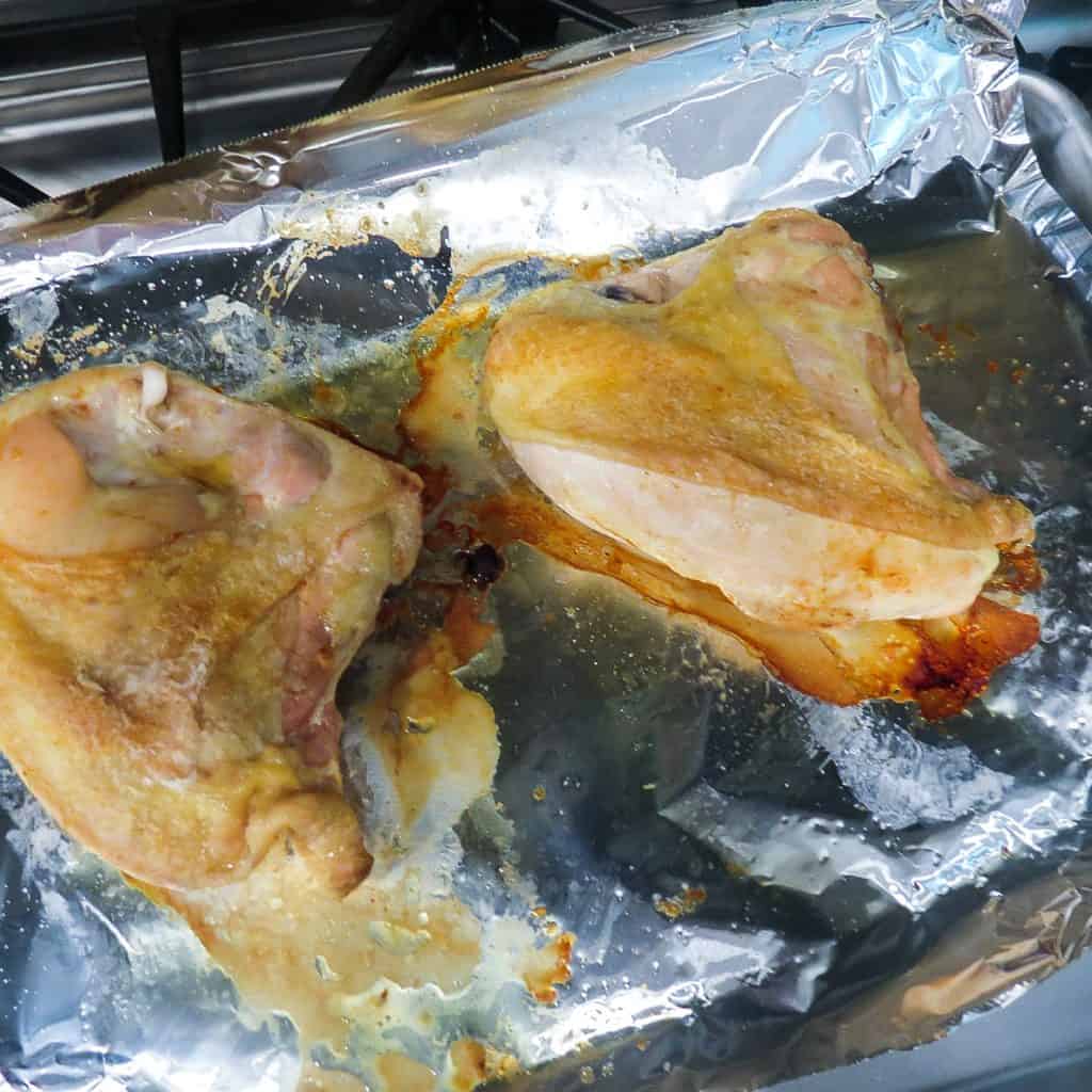 Roasted chicken breast on a foil lined pan for Chicken Salad With Green Peas.