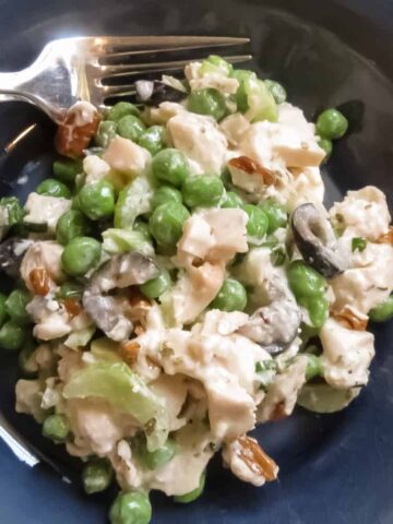 Chicken Salad With Green Peas in a blue bowl with a silver fork.
