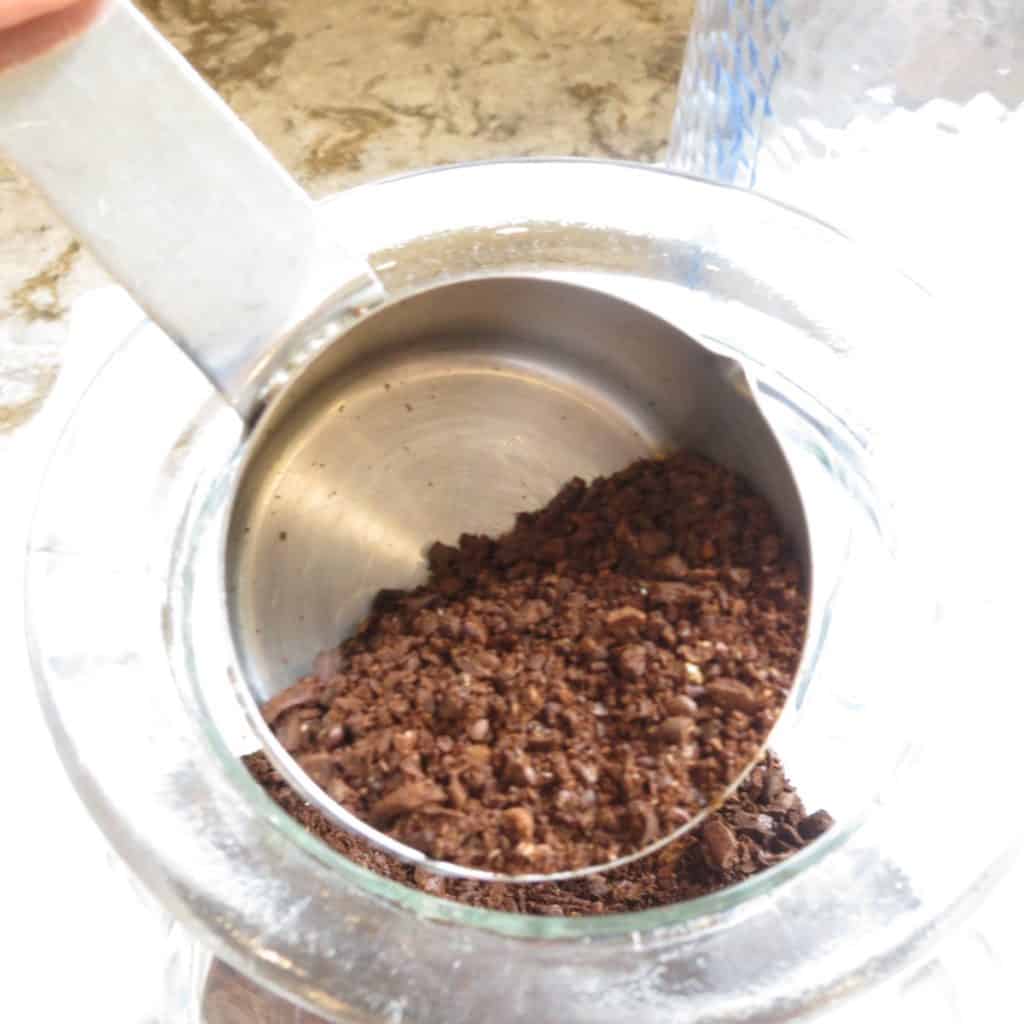 Coffee grounds poured into a glass jar.