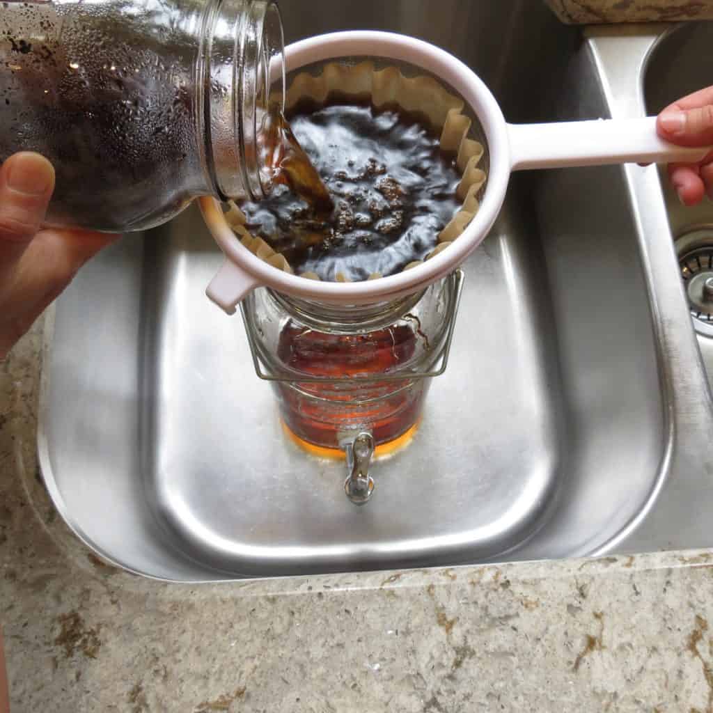Straining coffee into a pitcher from a jar.