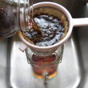 Straining coffee into a pitcher from a jar.