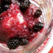 A dessert dish with blackberry and dumplings over ice ceam.