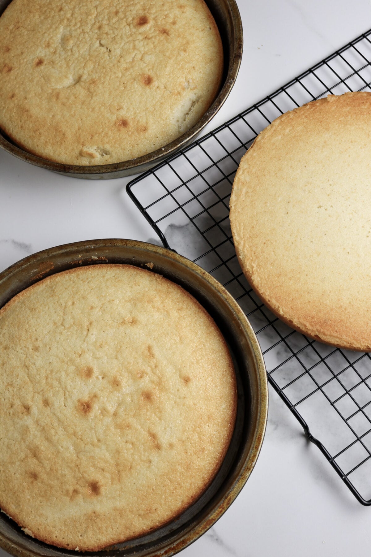 3 layers of round cake in pans and cooling on a wire rack.
