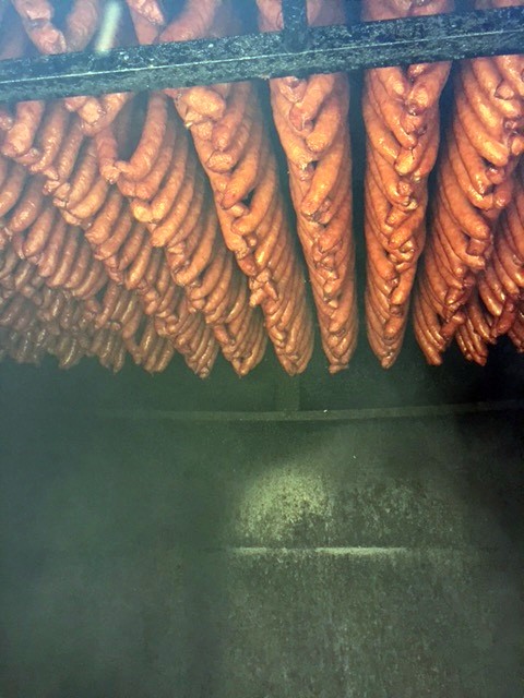 Sausage links hanging from the. ceiling of a smoke house.