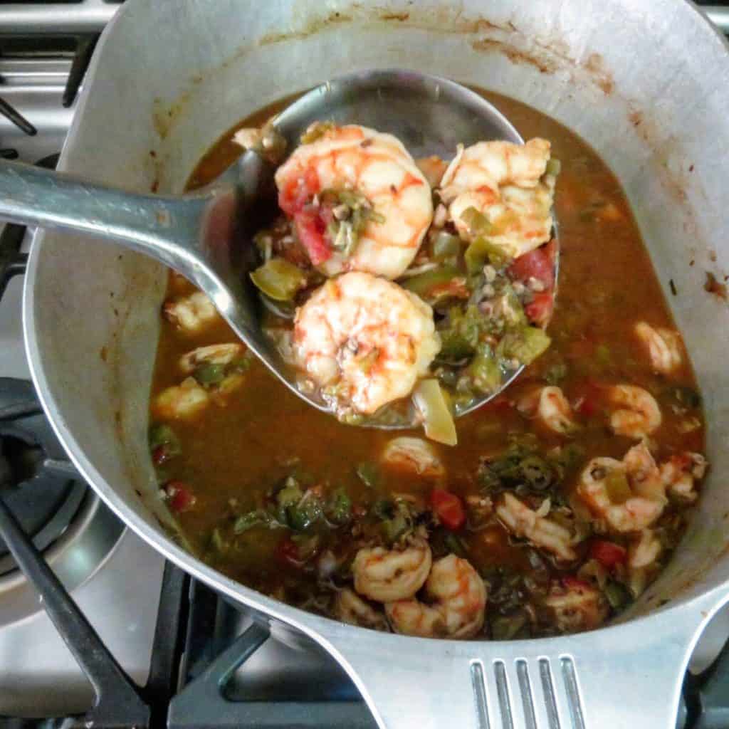 A label full of shrimp okra gumbo over a pot of gumbo.