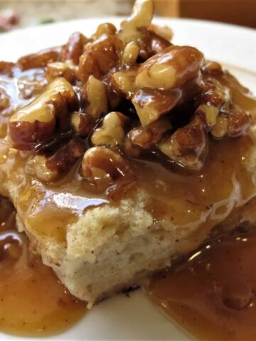 Bread Pudding topped with a Pumpkin Pecan Praline Sauce on white plate.