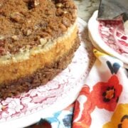 A pumpkin cheesecake sitting on a red and white toille plate.