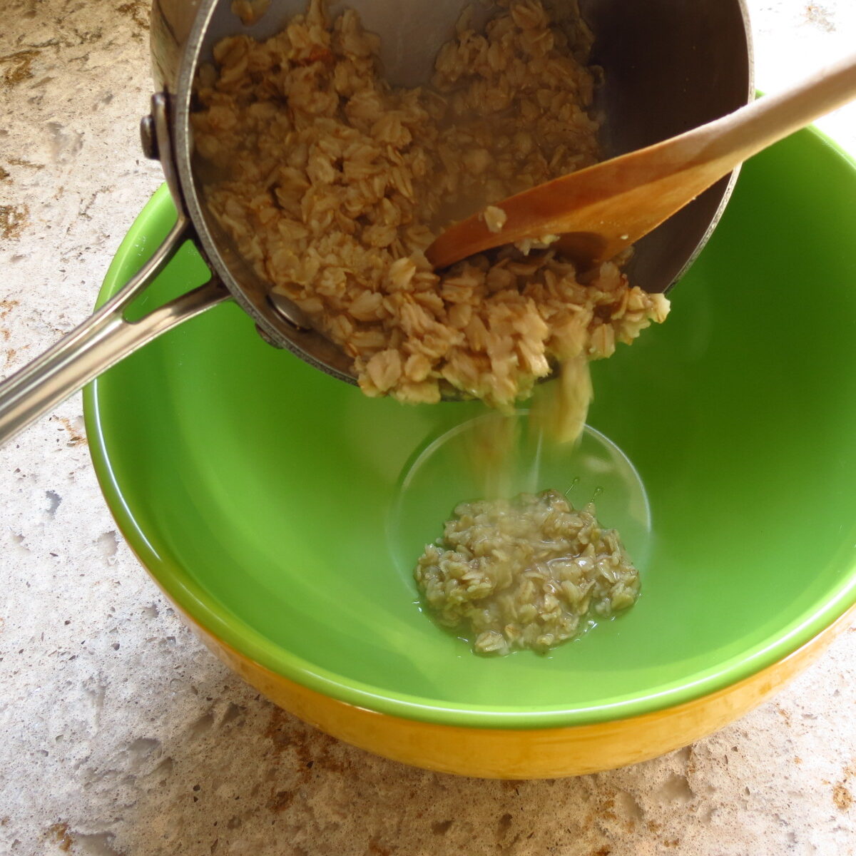 A saucepan of cooked oats poured into a large bowl.