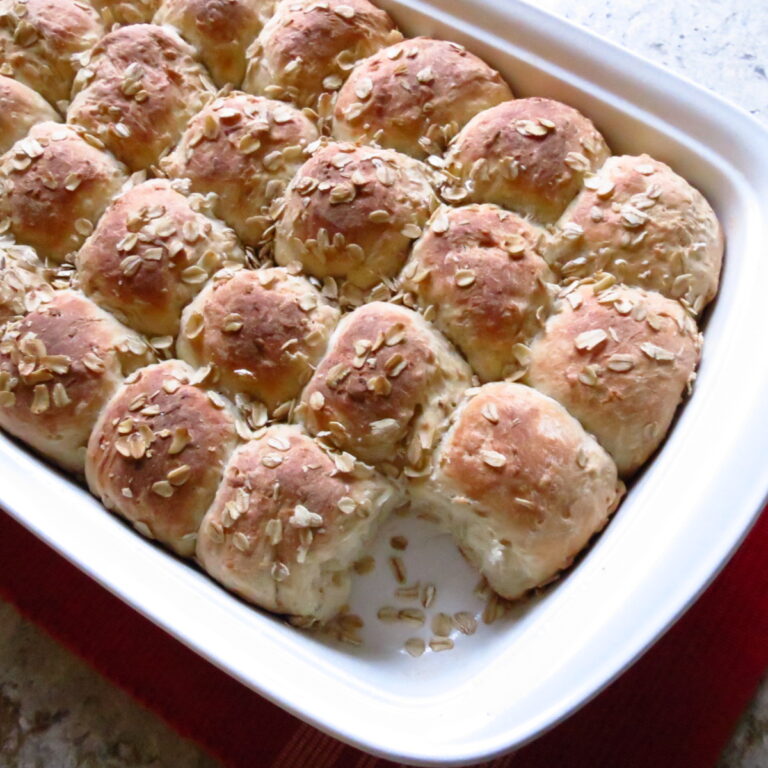 A white, rectangle pan of oatmeal rolls.