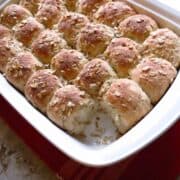 A white, rectangle pan of oatmeal rolls.