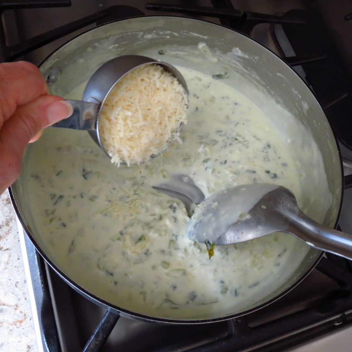 Cheese added to a pan of cream.