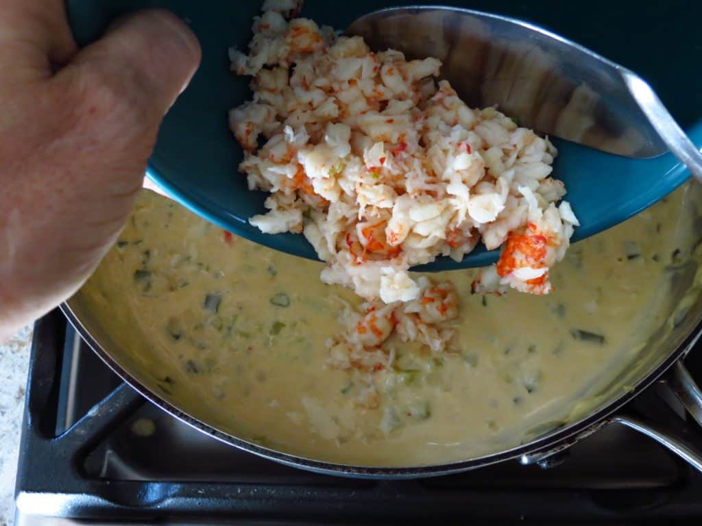 Crawfish poured into a pan of creamed mixture.