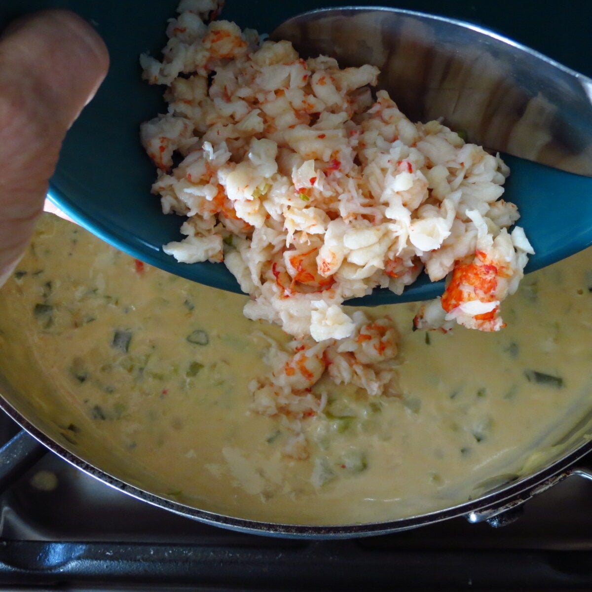 Crawfish poured into a pan of creamed mixture.