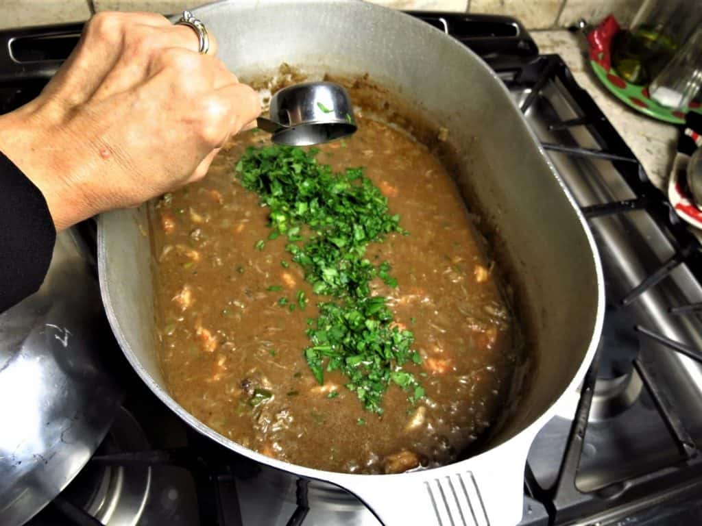 Chopped parsley and onion tops added to pot of gumbo.