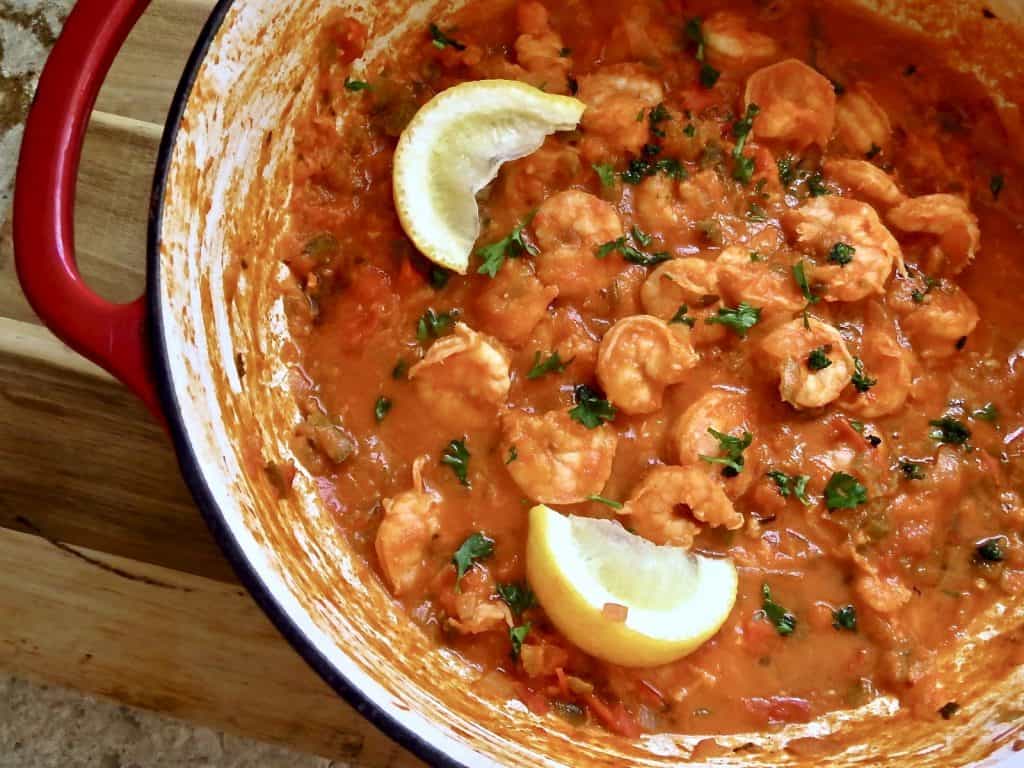 A pot of shrimp creole garnished with lemon wedges for Mardi Gras Food Recipes.