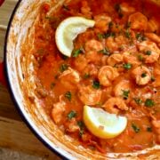 A pot of shrimp creole garnished with lemon wedges.