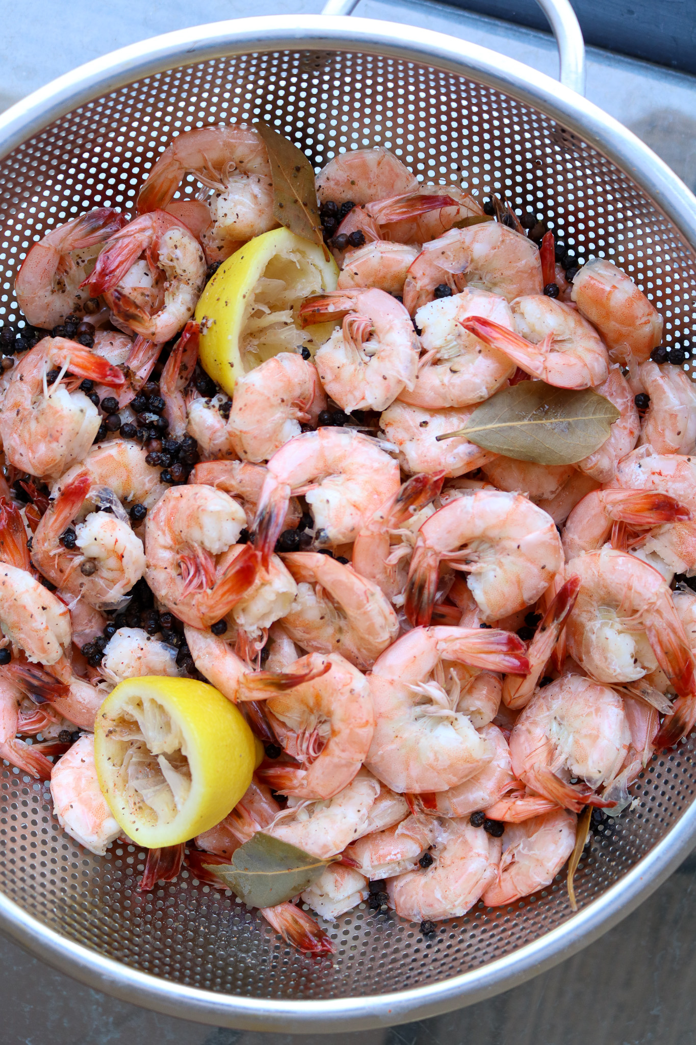 A pan of boiled shrimp with lemons, bay leaves, and seasonings.
