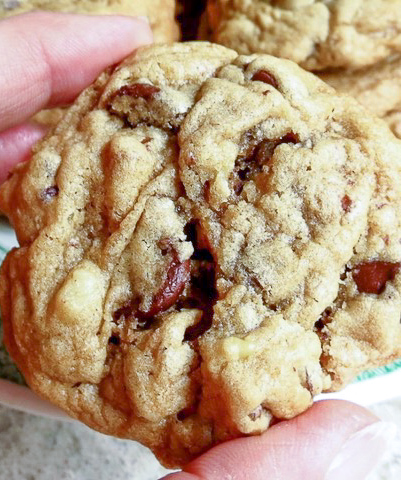 A hand holding chocolate chip cookie.