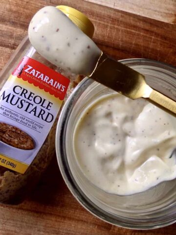 Overlooking Homemade Mayonnaise With A Creole Kick in a glass mason jar with a bottle of Zatarain's Creole Mustard next to it.