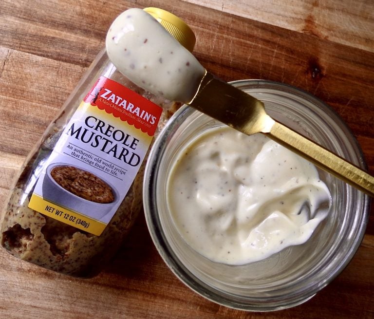 Overlooking Homemade Mayonnaise With A Creole Kick in a glass mason jar with a bottle of Zatarain's Creole Mustard next to it.